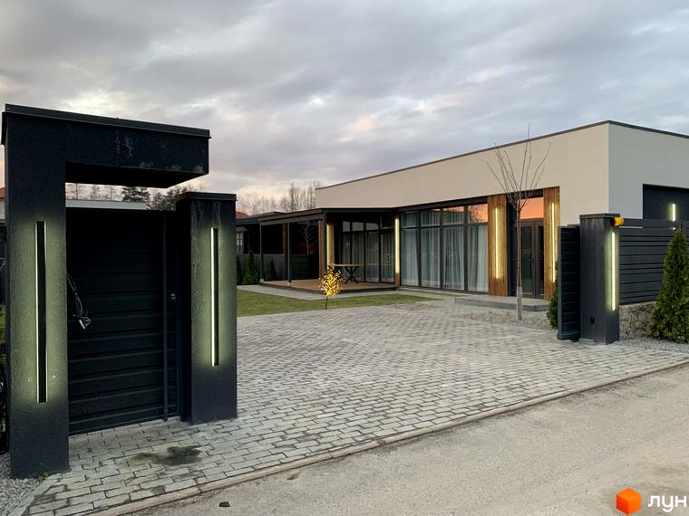 Котеджне містечко Romankiv House. Зовнішній вигляд будинку з великими вікнами, огородженою територією та освітленням.