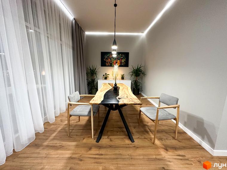 Інтер'єр їдальні в КМ Romankiv House з дерев'яним столом та сірими стільцями. Затишна атмосфера з природними елементами.