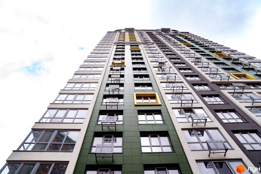 Висотна будівля Житлового комплексу Паркове місто з багатокольоровим фасадом. Фасад має секції зеленого, бежевого та темно-сірого кольорів з жовтими акцентами.