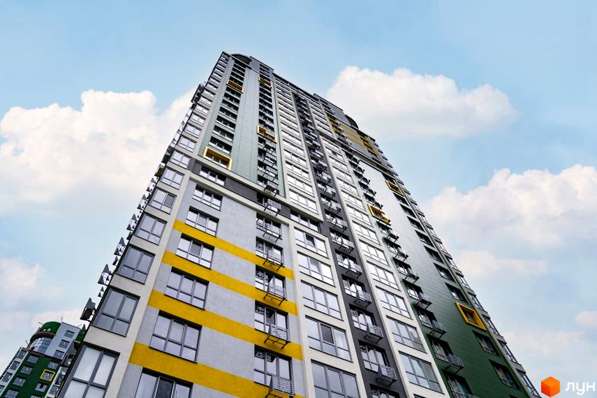 Фасад багатоповерхового будинку Житлового комплексу Паркове місто з контрастними сірими, зеленими та жовтими смугами. Вид на будівлю на тлі неба з хмарами.
