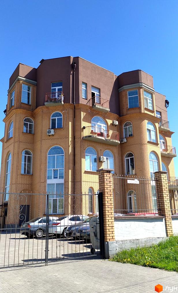 Житловий комплекс Жулянський - цегляна новобудова з арочними вікнами та балконами, огороджена територія з паркуванням.