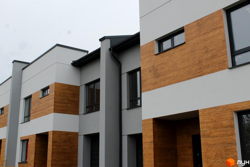 Фасад таунхаусу «Пронятин» з дерев'яним оздобленням. Сірі стіни, великі вікна та мінімалістичний дизайн. Новобудова з продуманою архітектурою.
