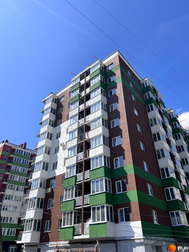 Зовнішній вигляд житлового комплексу Eco House з коричнево-зеленими фасадами та численними вікнами. Будинки мають багатоповерхову забудову з балконами та лоджіями.