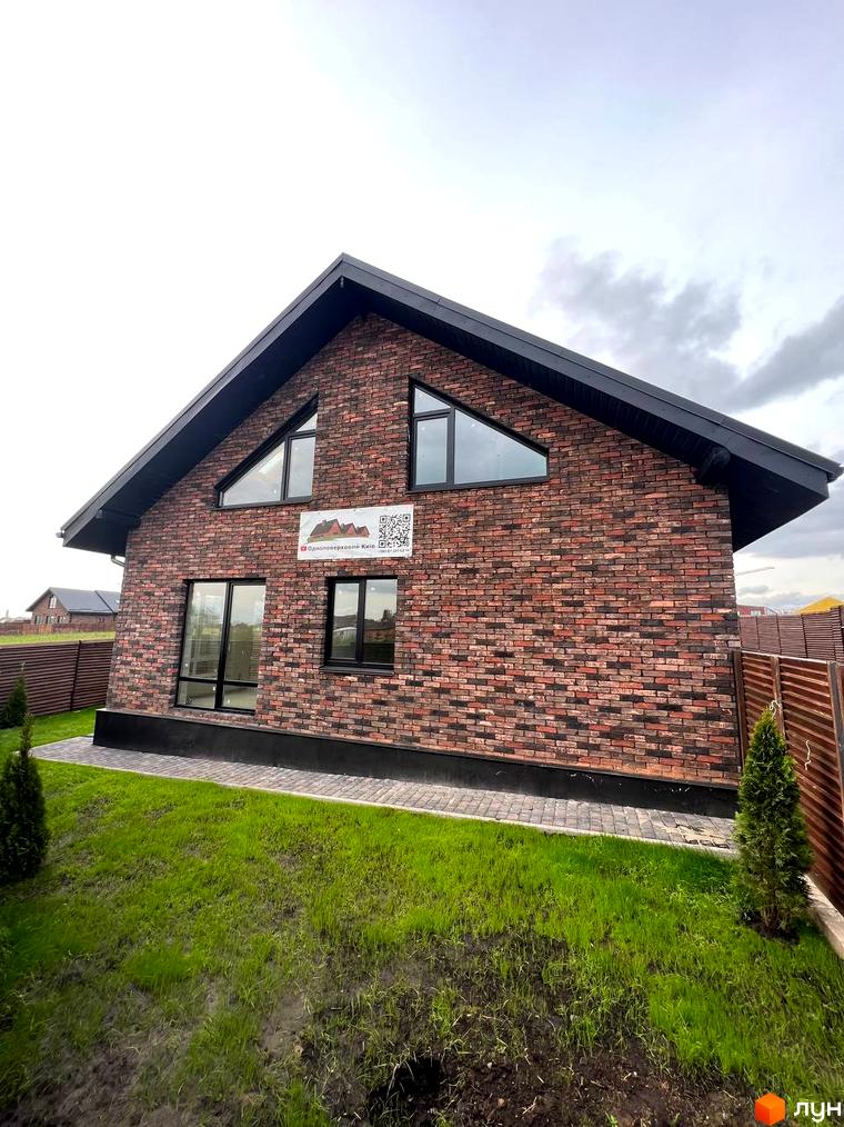 Котеджне містечко Квартал Баварія: двоповерховий будинок з червоної цегли з великими вікнами та зеленою галявиною перед ним.