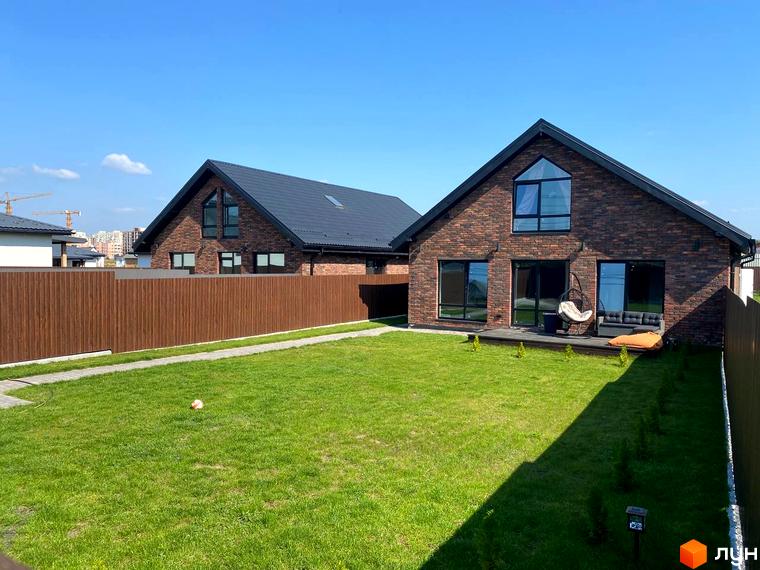 Дуплекси Одноповерховий Київ - Солонка. Цегляний будинок з великими вікнами та доглянутою зеленою ділянкою з газоном та дерев'яною терасою.