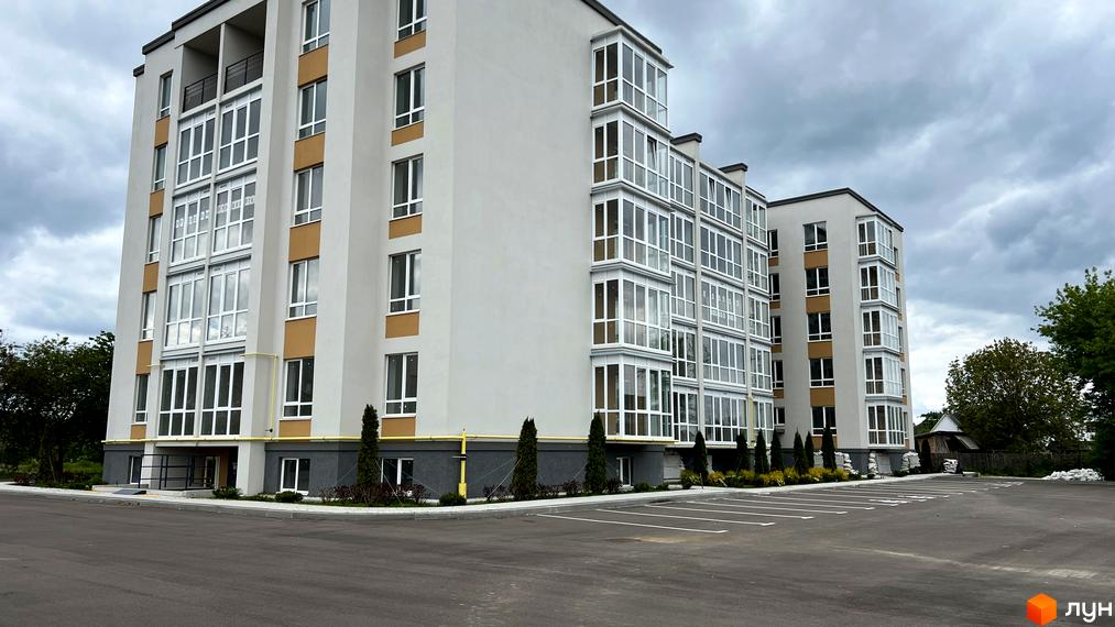 Зовнішній вигляд новобудови ЖК Сімейний з численними вікнами та балконами. На прибудинковій території облаштовано паркінг.