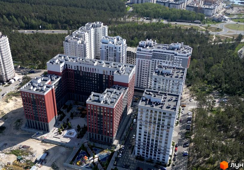 Фото багатоповерхових будинків Житлового комплексу Irpin City з червоними та чорними фасадами. На території є дитячий майданчик, пісочниця та зелені насадження.