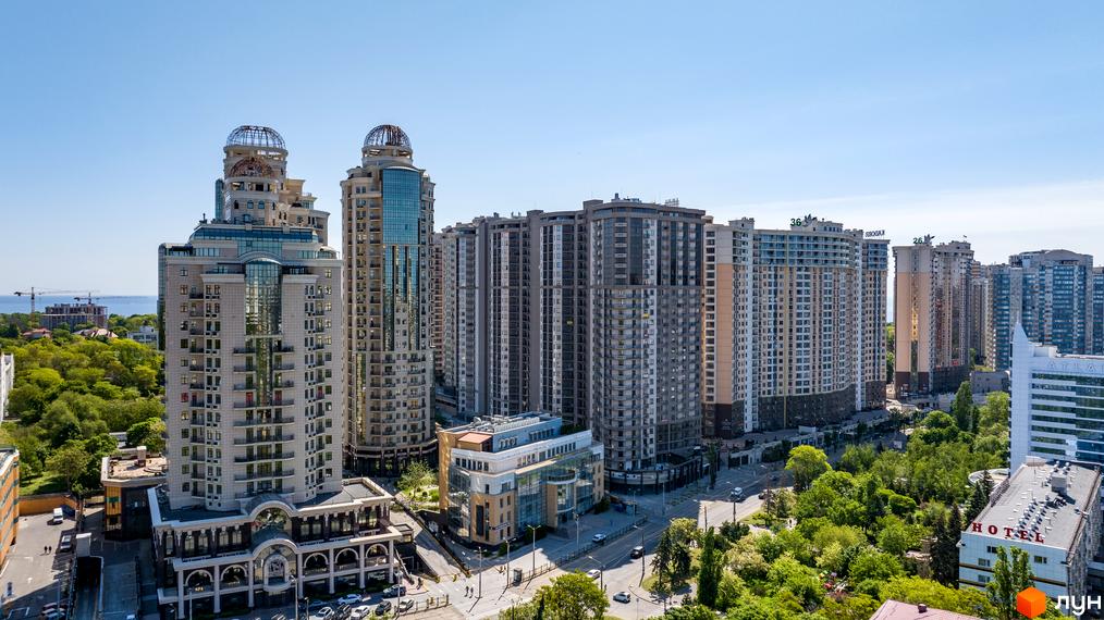 Житловий комплекс Родос: панорама висотних будівель з купольними завершеннями. Комплекс оточений зеленими насадженнями та дорогами, з видом на море.