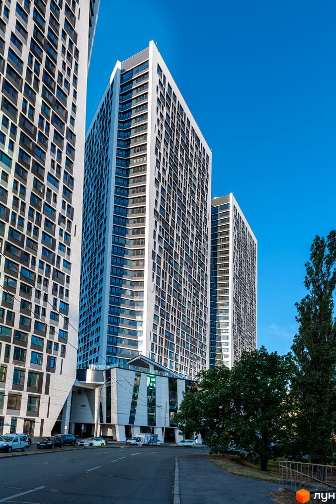 Житловий комплекс Manhattan city – це сучасні висотні будинки з панорамними вікнами та великою кількістю скла. Навколо комплексу розташовані дерева та облаштована прибудинкова територія.