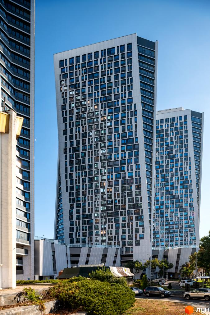Житловий комплекс Manhattan city - висотні будинки з незвичайною архітектурою та панорамними вікнами. Навколо комплексу зелена зона та парковка.