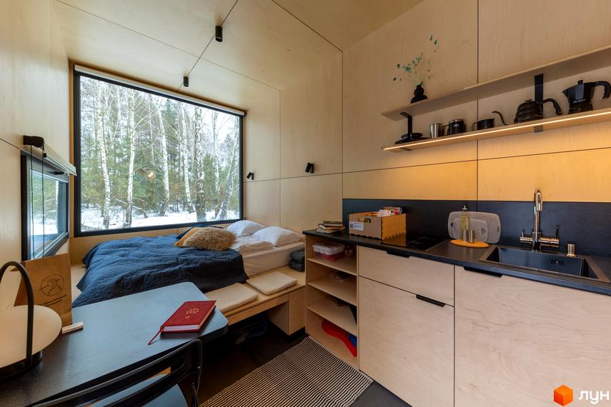 Затишна кімната з великим вікном, що виходить на зимовий ліс, та міні-кухнею. Комплекс УЛІС – ваш простір для життя в природі.