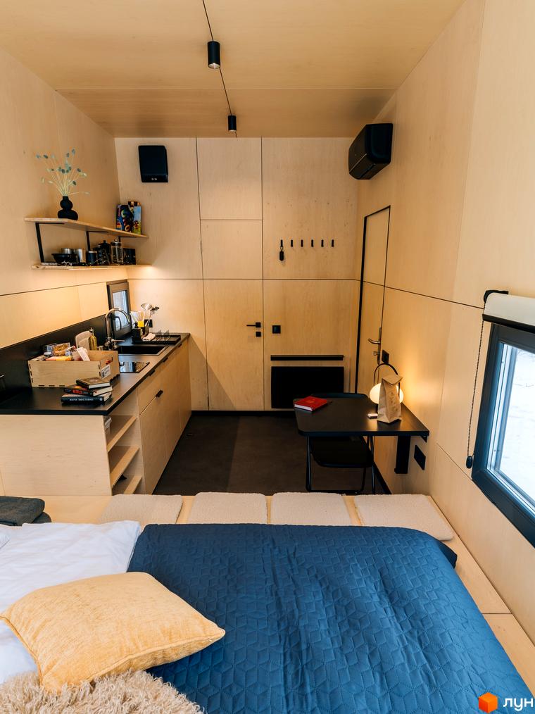 Інтер'єр компактного житлового комплексу УЛІС з кухнею, спальним місцем та робочим столом.
