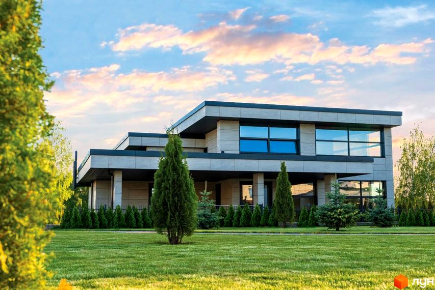 Котеджне містечко DAMBA RIVER PARK: двоповерховий будинок з великими вікнами та зеленою галявиною перед ним. Навколо будинку розташовані дерева та кущі.