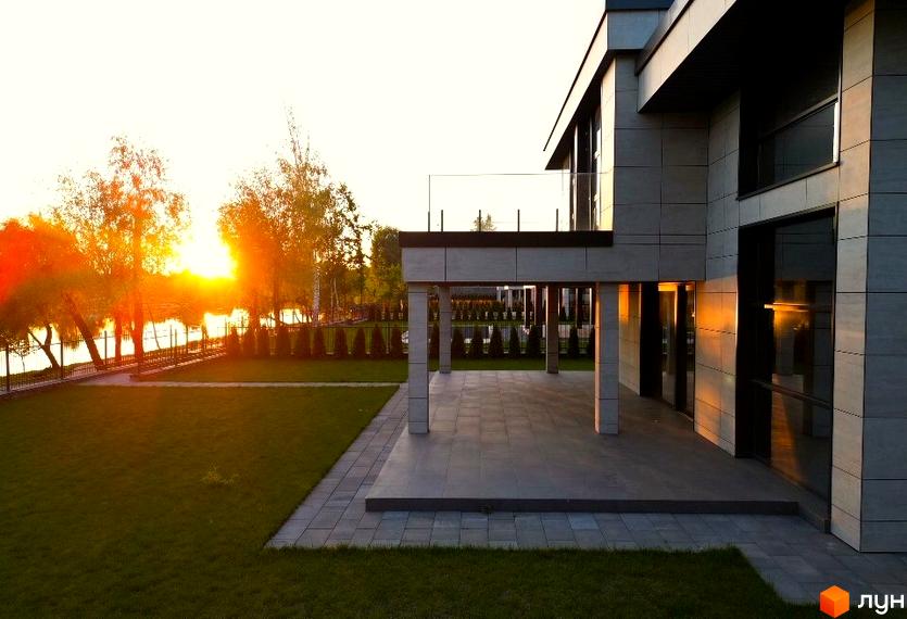 Котеджне містечко DAMBA RIVER PARK з терасою та панорамними вікнами, що виходить на зелену галявину та річку.