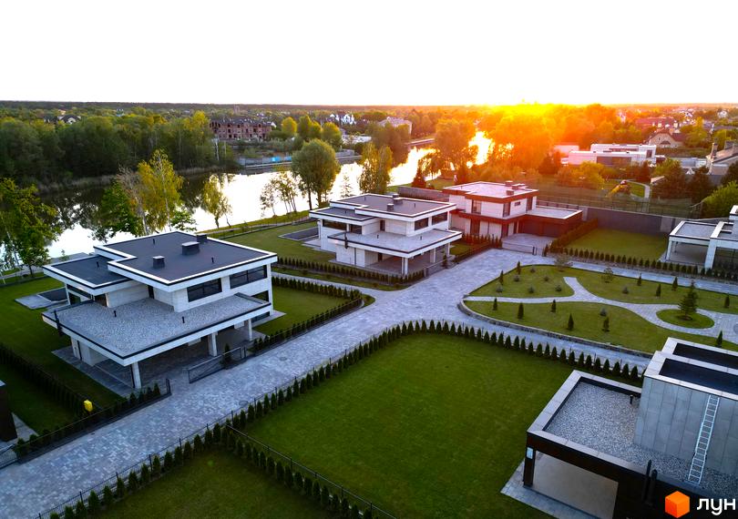 Котеджне містечко DAMBA RIVER PARK з сучасними будинками та доглянутою прибудинковою територією біля річки.