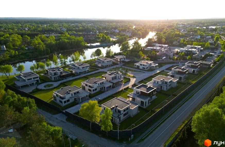 Котеджне містечко КМ DAMBA RIVER PARK з сучасними будинками та доглянутою прибудинковою територією біля річки.