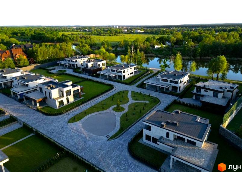 Котеджне містечко КМ DAMBA RIVER PARK. Сучасні будинки з пласкими дахами та великими вікнами, розташовані біля річки на доглянутій території з зеленими газонами та доріжками.