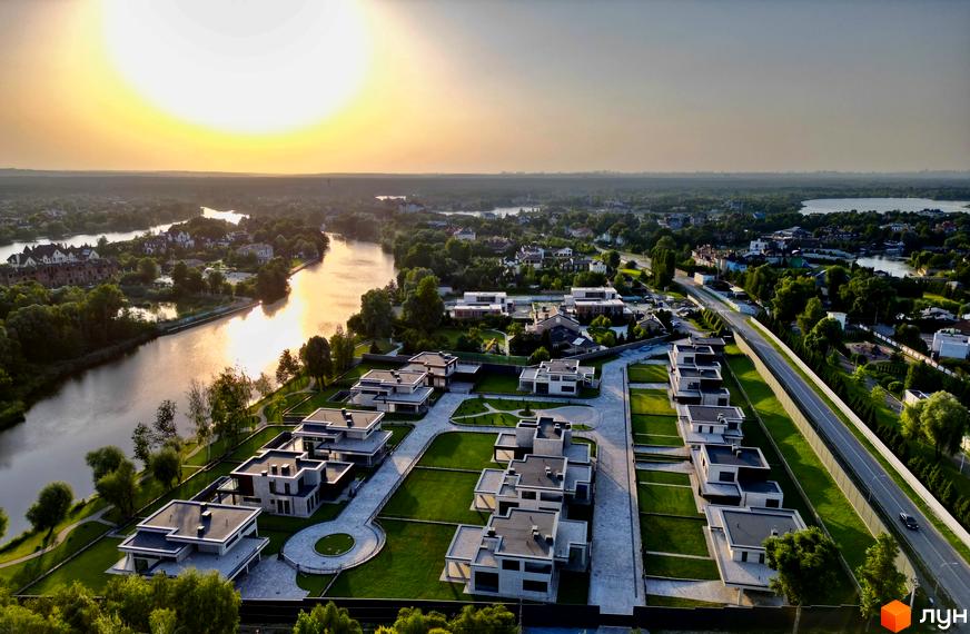 Котеджне містечко DAMBA RIVER PARK з сучасними будинками та доглянутою прибудинковою територією біля річки.