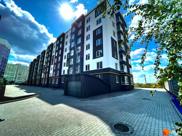 Житловий комплекс Петрівські Липки - сучасна новобудова з чорно-білим фасадом та облаштованою прибудинковою територією. Фотографія демонструє будівлю та вимощену бруківкою площу.