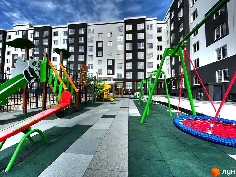 Багатоповерховий будинок житлового комплексу Петрівські Липки з дитячим майданчиком на прибудинковій території.