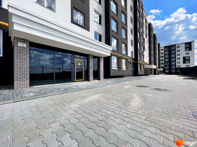 Фасад багатоповерхового будинку Житловий комплекс Петрівські Липки з панорамними вікнами та бруківкою на прибудинковій території.