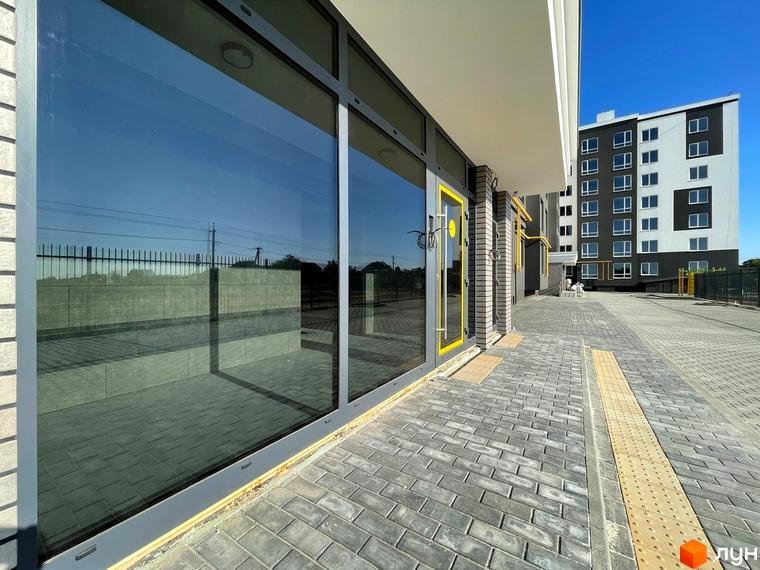 Зовнішній вигляд новобудови ЖК Петрівські Липки з великими вікнами та бруківкою на прибудинковій території.