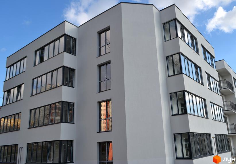 Зображення фасаду Житлового комплексу На Нивах, 15. Багатоповерхова будівля з великими вікнами та світлим оздобленням.