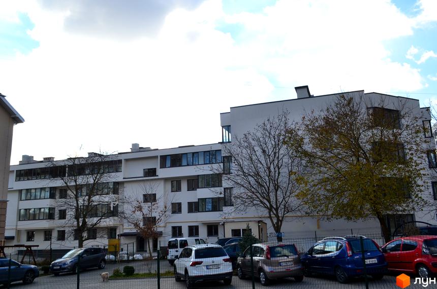 Зовнішній вигляд будинку житлового комплексу ЖК На Нивах, 15, з парковкою та деревами на прибудинковій території.