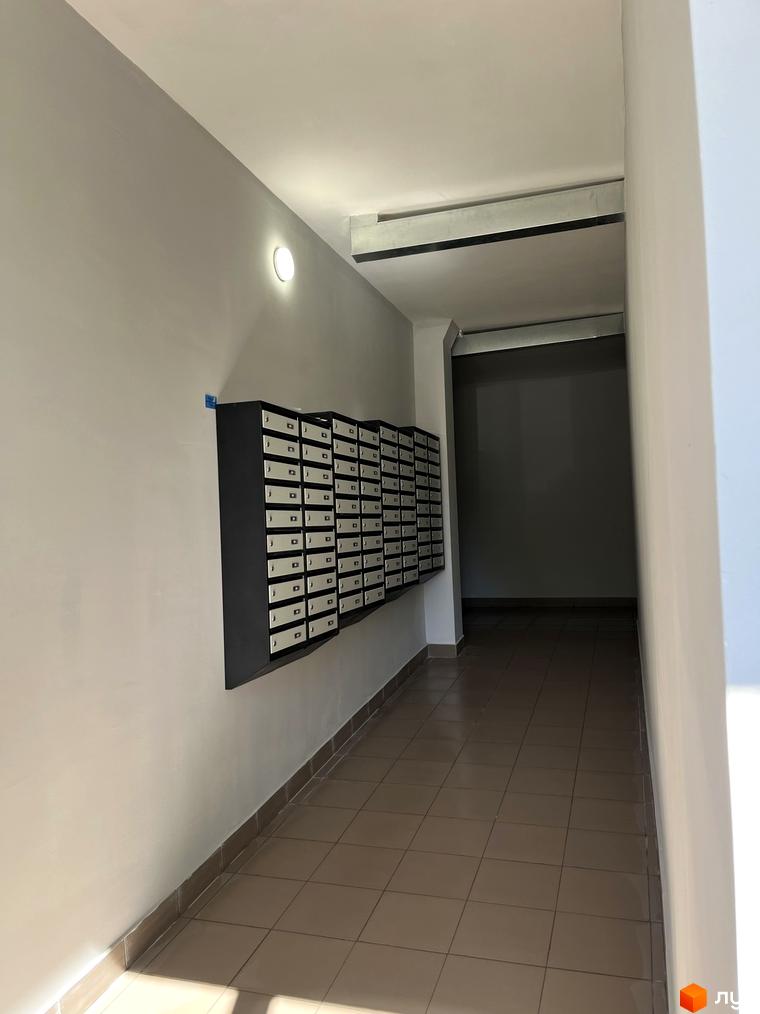 Внутрішній коридор Новобудови на вул. Тараскова, 5 з рядами поштових скриньок та плитковою підлогою.