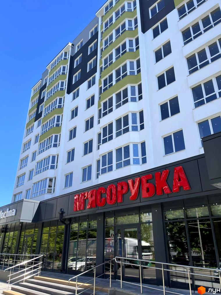 Висотна новобудова з великою кількістю вікон та магазином на першому поверсі. На вулиці Тараскова, 5.