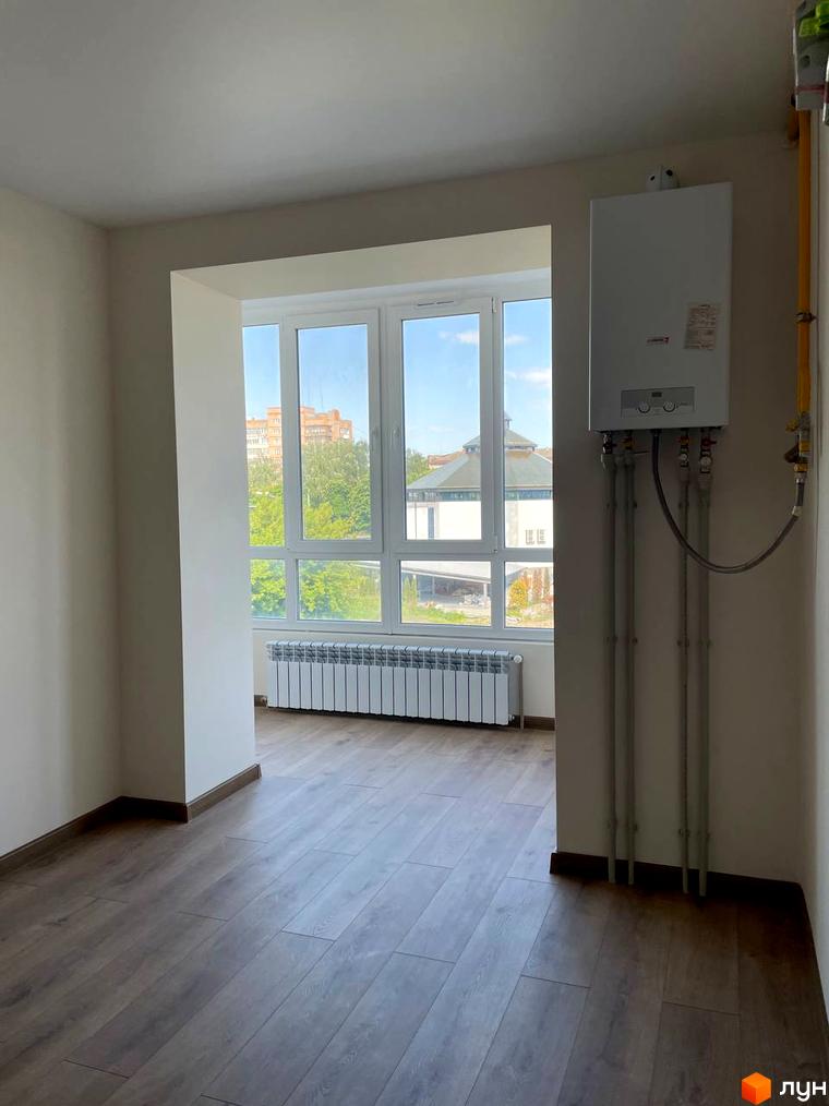 Вид на міську забудову та зелень з вікна квартири в Житловому комплексі Сім'я. Інтер'єр: світлі стіни, ламінат, газовий котел.