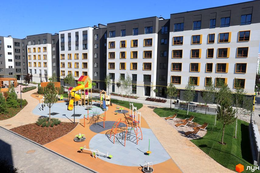 Житловий комплекс Молодість з яскравим дитячим майданчиком та зонами відпочинку. Сучасні фасади будівель з жовтими вікнами створюють привабливий вигляд.