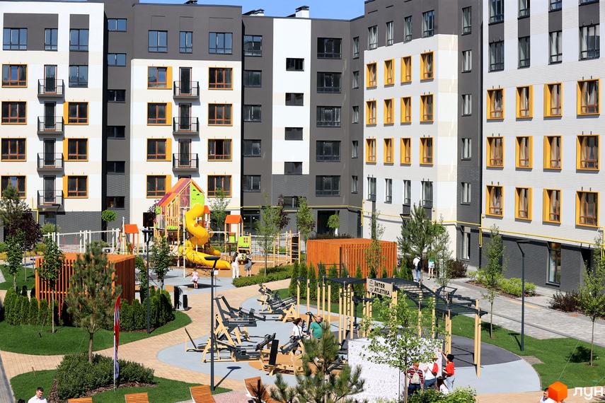 Житловий комплекс Молодість з яскравим дитячим майданчиком та зоною для спорту на прибудинковій території. Будинки мають біло-сіре оздоблення з жовтими акцентами.