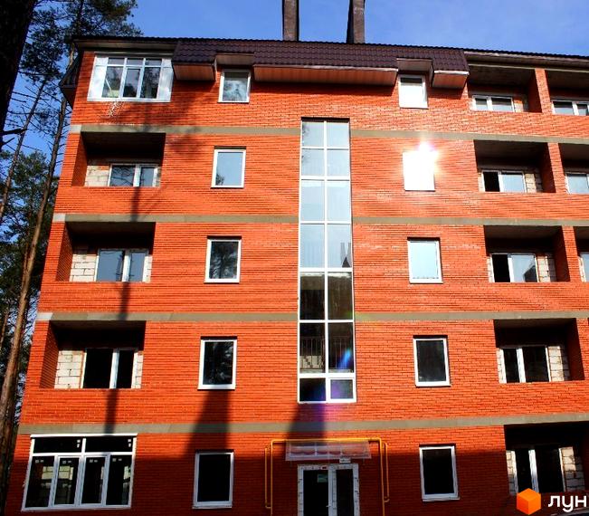 Новобудова ЖК Зелений квартал з червоної цегли з великими вікнами. Зовнішній вигляд фасаду будівлі.