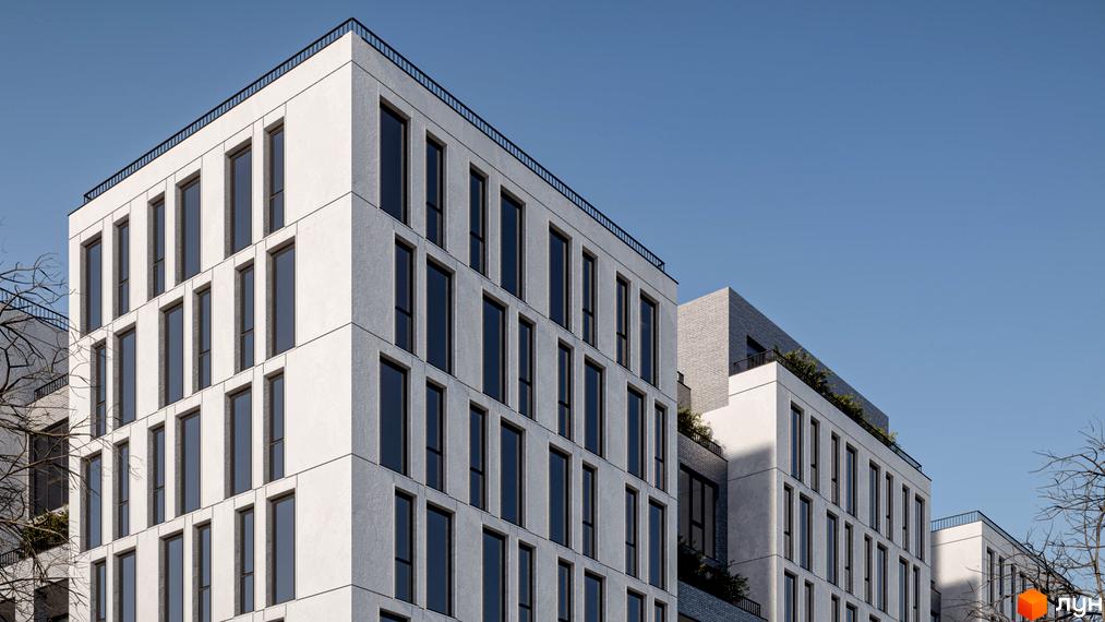 Житловий комплекс Art deluxe - це сучасна новобудова з білими фасадами та великими вікнами, що виглядає елегантно на тлі блакитного неба. Навколо будівлі видно зелені насадження та дерева.