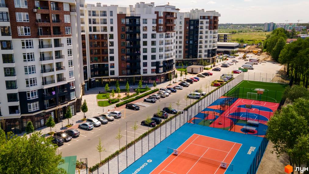 Житловий комплекс Синергія Сіті з багатоповерховими будинками та спортивними майданчиками. На території комплексу розташовані паркувальні місця та зелені зони.