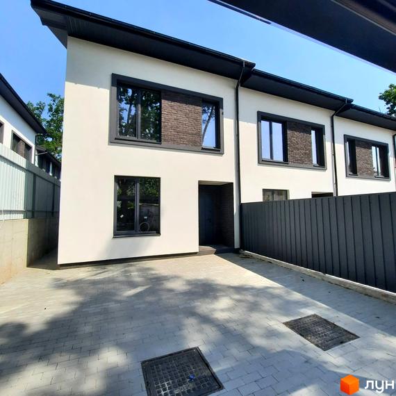 Таунхауси Т-35: Білі двоповерхові будинки з темними віконними рамами та коричневими цегляними вставками. Прибудинкова територія вимощена сірою бруківкою.