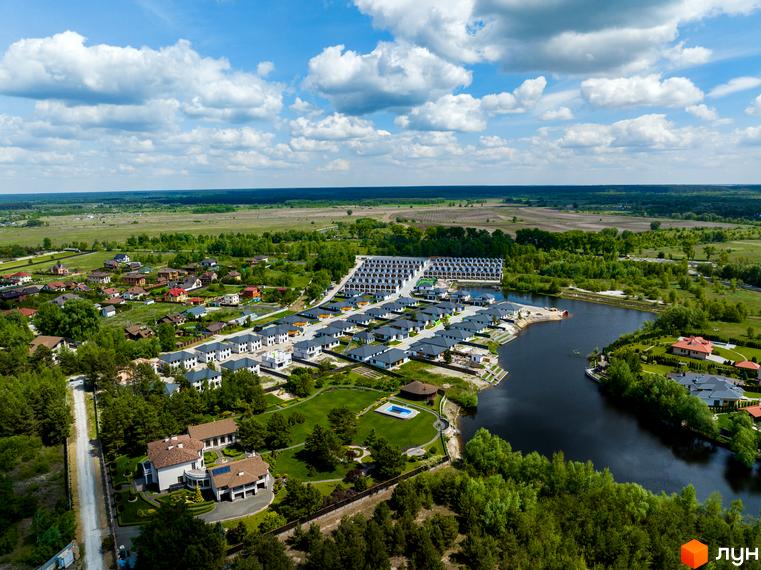 Зображення Котеджного містечка Prydesennya Eco Village з висоти пташиного польоту. Видно будинки з темними дахами та велику прибудинкову територію з озером.