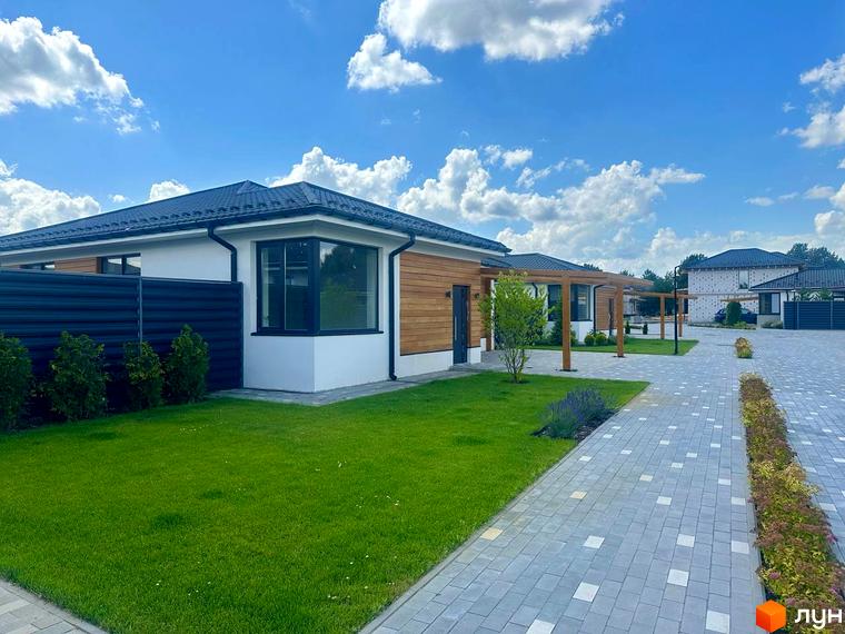 Зовнішній вигляд та прибудинкова територія Котеджного містечка Prydesennya Eco Village. Одноповерхові будинки з газоном та доріжками.