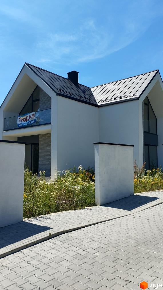 Сучасний будинок з металевим дахом та великими вікнами на вулиці Північна. Прибудинкова територія з бруківкою та зеленню.