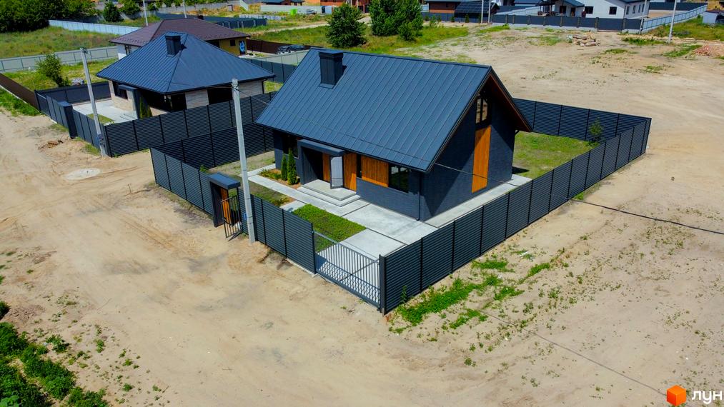 Котеджне містечко SMADE Park: одноповерховий будинок з темним фасадом та сірим дахом, огороджена ділянка з доглянутим газоном.