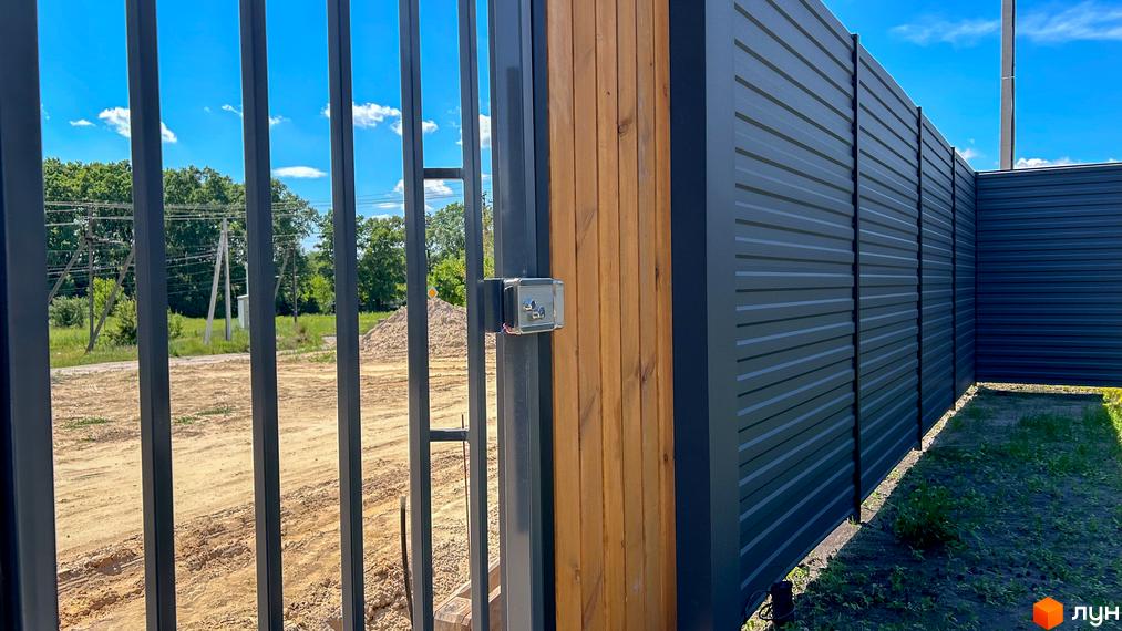 Котеджне містечко SMADE Park: паркан з металопрофілю та дерев'яних елементів з воротами. Прибудинкова територія з травою та піском.