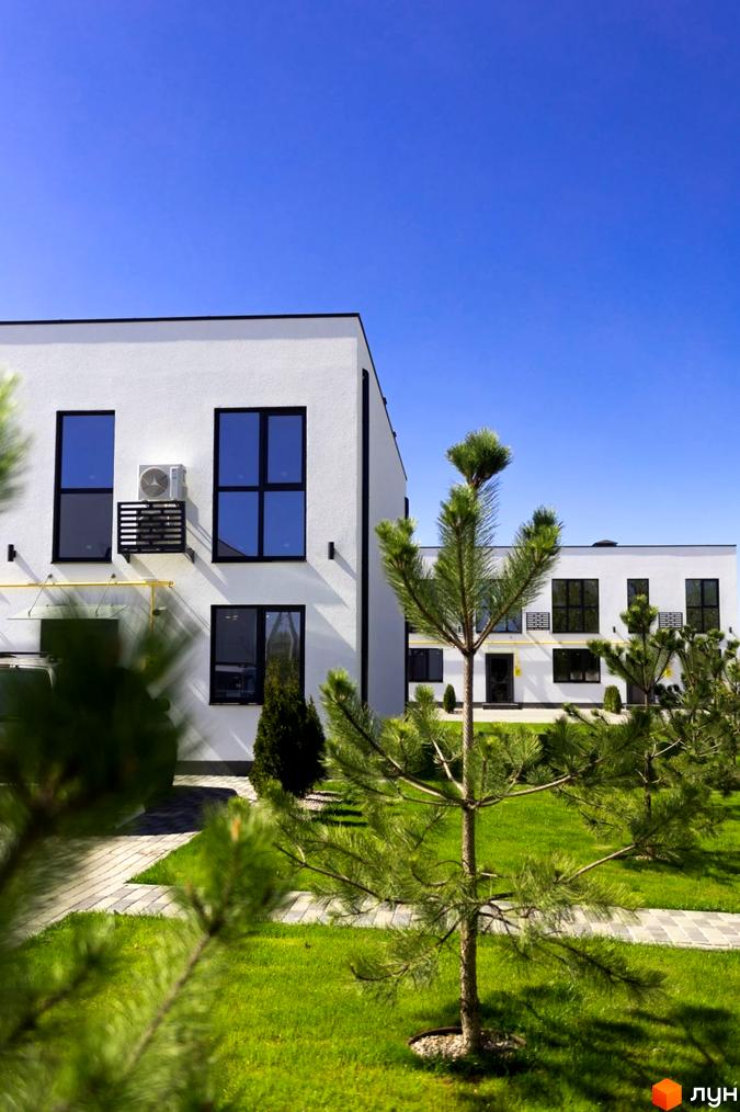 Таунхауси DREAM HOUSE – білі двоповерхові будинки з темними вікнами та кондиціонерами. Навколо зелений газон та доріжки з бруківки.