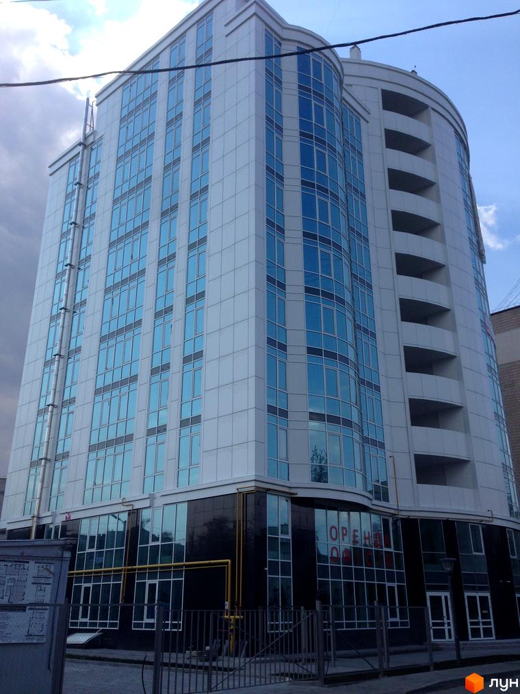 Житловий комплекс Атлантіс – висотна будівля з панорамними вікнами та балконами. Фасад оздоблений білими панелями та темною основою.