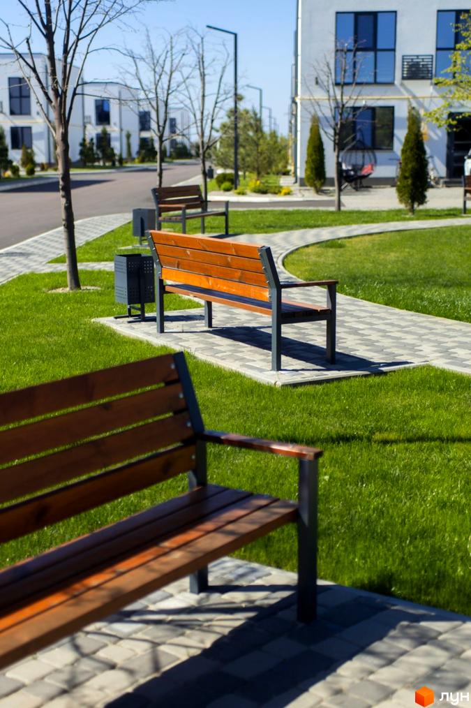 Таунхауси DREAM HOUSE: білі двоповерхові будинки з великими темними вікнами, доглянуті газони, вимощені доріжки та дерев'яні лавки.