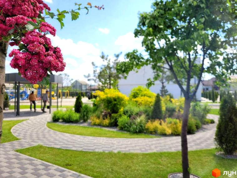 Таунхауси DREAM HOUSE з доглянутою прибудинковою територією та зеленими насадженнями. Зелена зона з доріжками та дитячим майданчиком біля будівель.