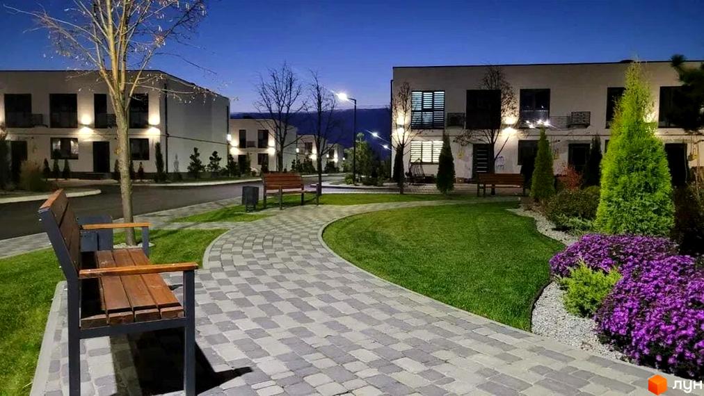 Таунхауси DREAM HOUSE з підсвіченими фасадами та доглянутою прибудинковою територією з доріжками та зеленими насадженнями.