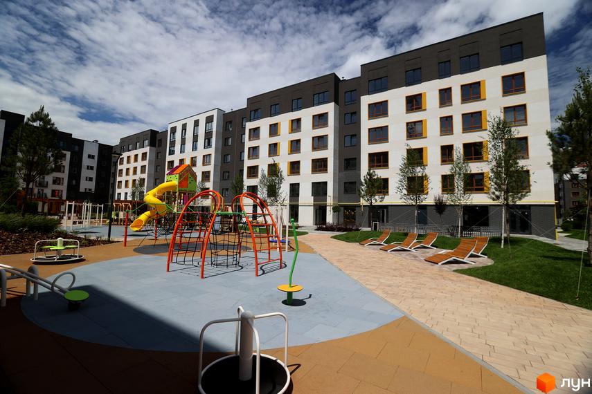 Житловий комплекс Молодість. Сучасна архітектура будівель з білими та темними фасадами, жовтими акцентами на вікнах. На прибудинковій території дитячий майданчик та зони відпочинку.