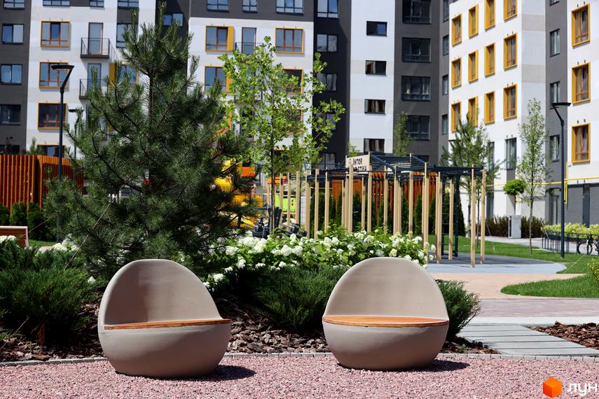 Житловий комплекс Молодість: фасади будинків з жовтими вікнами та прибудинкова територія з ландшафтним дизайном та місцями для відпочинку.