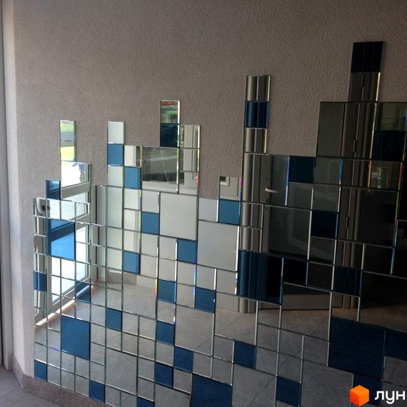 Декоративна стіна з дзеркальних та синіх квадратів у житловому комплексі Атлантіс. Дизайн стіни нагадує піксельний малюнок або міський пейзаж.